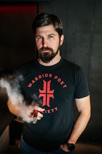 a man with a beard smoking a cigarette in a dark room
