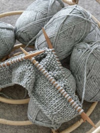 grey yarn and knitting needles in a basket