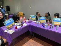 a group of people sitting around a table painting