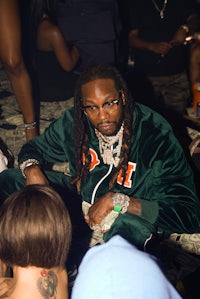 a man with dreadlocks sitting next to a group of people