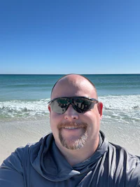 a man wearing sunglasses taking a selfie on the beach