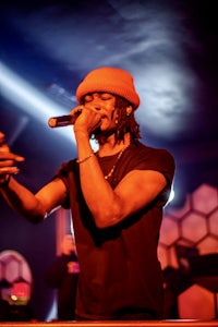a man in an orange hat singing into a microphone