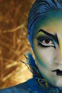 a woman with blue makeup and feathers on her face