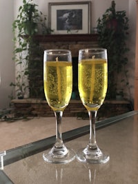 two glasses of wine on a table in front of a fireplace