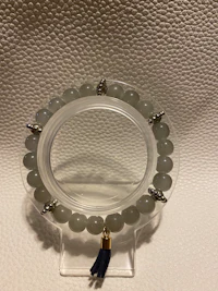 a bracelet with grey jade beads on a white surface