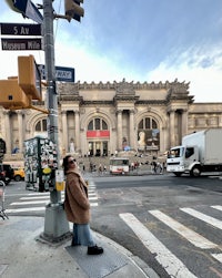 a woman standing on a street corner in front of a building