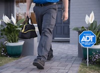 a man walking down the street with an adt sign