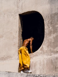 a man is standing on a ledge looking out of a window