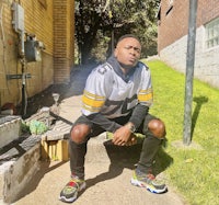 a man crouching on a curb in front of a house