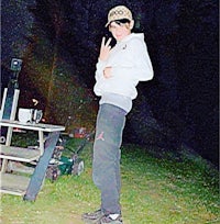 a young man standing next to a picnic table at night