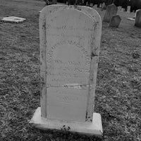 a black and white photo of a tombstone in a cemetery