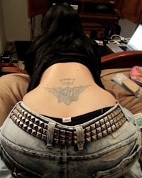 a woman sitting on a bed with a tattoo on her back