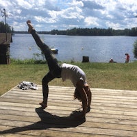 a woman doing a yoga pose on a wooden deck