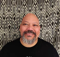 a man with a beard smiling in front of a patterned wall