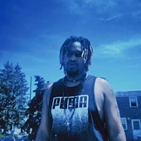 a man with dreadlocks standing in a parking lot