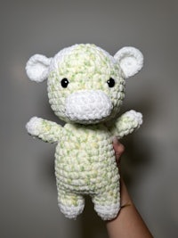 a person holding a crocheted blue and white cow