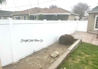 a white fence in a backyard with a sign on it