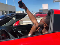 a man in a red sports car taking a selfie