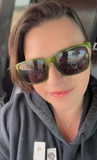 a woman wearing sunglasses in the back seat of a car