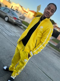 a man in a yellow tracksuit standing on a street