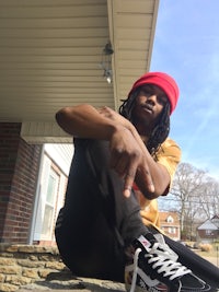 a man wearing a red beanie sitting on a brick wall