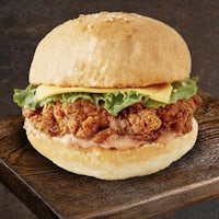 a fried chicken sandwich is sitting on a wooden table