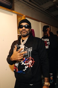 a man in a black hoodie standing in a closet