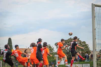 a group of soccer players jumping for a ball