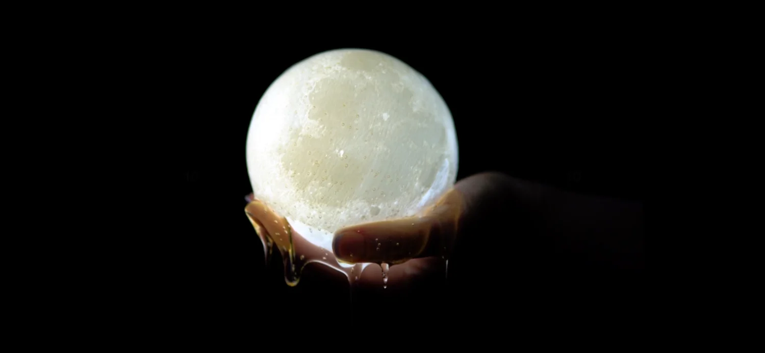 a person holding a white egg in front of a dark background