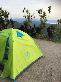 a green tent sitting on a dirt road
