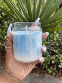 a hand holding a blue and white candle