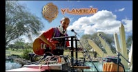 a man is playing an acoustic guitar in front of a lake