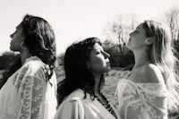 three women in white dresses standing in a field