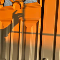 a shadow of a hand on an orange door