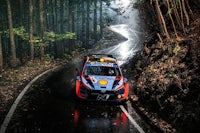 a rally car driving down a road in the rain