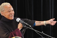 a woman with a tattoo on her arm is speaking into a microphone