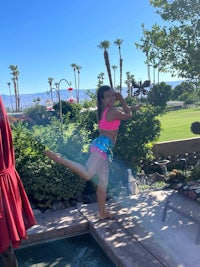 a woman in a bikini standing next to a pool