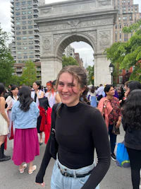 a woman is smiling in front of an arch