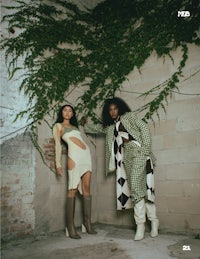 two women standing next to each other in front of a wall