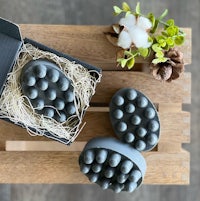 two black soaps in a box on top of a wooden table