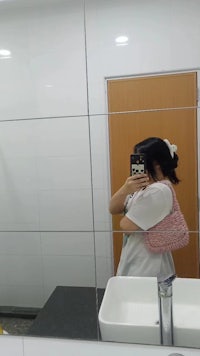 a woman taking a selfie in a bathroom mirror