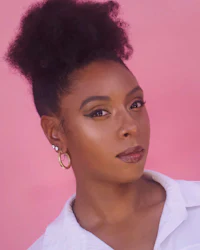 a woman in a white shirt with an afro and hoop earrings