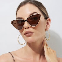 a woman wearing brown cat eye sunglasses and gold hoop earrings