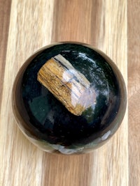 a black and green glass ball on a wooden table
