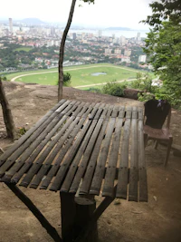 a wooden bench on top of a hill overlooking a city