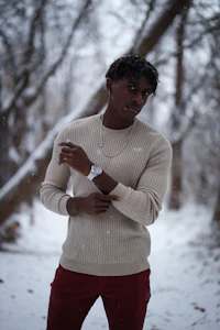 a man standing in the snow wearing a sweater and red pants