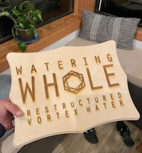 a man holding up a sign that says watering whole reconstructed vortex water