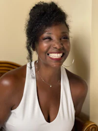 a smiling woman in a white top sitting on a chair