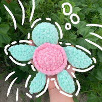 a hand holding a crocheted pink and green turtle