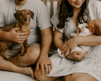 a man and woman holding a baby and a dachshund